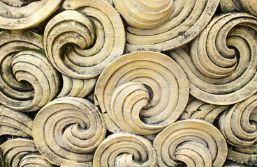 Close up of old yellow concrete swirls design on wall in Bali. background and wallpaper texture