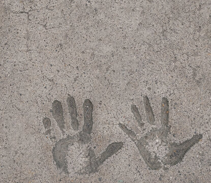 Two hand prints in tan concrete pavement background and wallpaper texture. Copy space