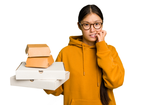 Young student asian woman holding a takeaway food isolated biting fingernails, nervous and very anxious.