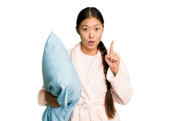Young asian woman wearing a pajama holding a pillow isolated having some great idea, concept of creativity.