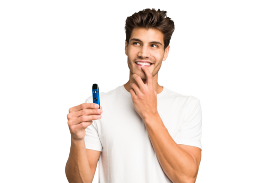Young caucasian man holding an electronic cigarette isolated relaxed thinking about something looking at a copy space.