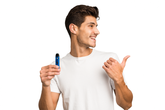 Young caucasian man holding an electronic cigarette isolated points with thumb finger away, laughing and carefree.