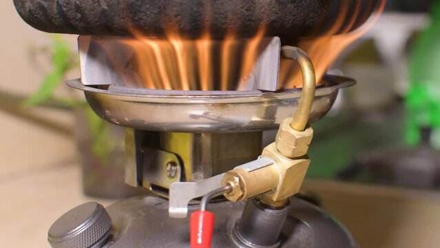 Food Cooking On Small portable Kerosene camp stove with red flame burns, close up