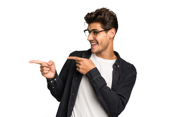 Young caucasian handsome man isolated points with thumb finger away, laughing and carefree.