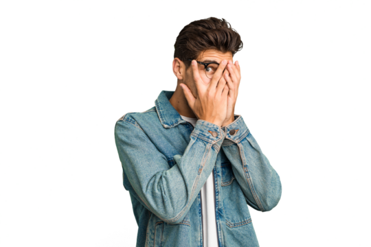 Young caucasian handsome man isolated blink through fingers frightened and nervous.