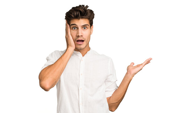 Young caucasian handsome man isolated impressed holding copy space on palm.