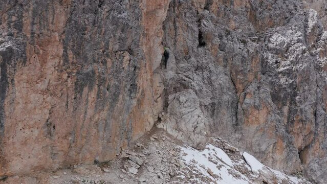 Mountain climber ascending via ferrata Oskar Schuster, rocky mountain side, Sassolungo mountain Dolomites, Italy