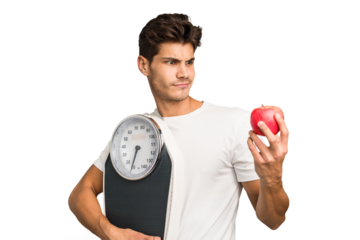 Young caucasian man holding a scale and an apple isolated