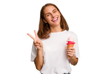 Young caucasian woman holding an ice cream isolated joyful and carefree showing a peace symbol with fingers.