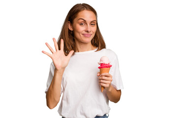Young caucasian woman holding an ice cream isolated smiling cheerful showing number five with...