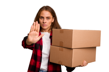 Young caucasian woman moving while picking up a box full of things isolated standing with outstretched hand showing stop sign, preventing you.