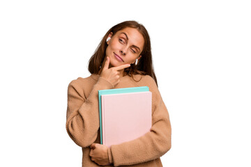 Young student woman holding a books isolated looking sideways with doubtful and skeptical expression.