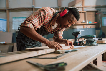 African carpenter measuring wood and timber with electric tools