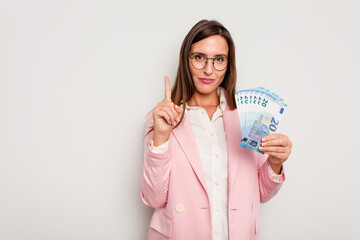 Business caucasian woman holding banknotes isolated on white background showing number one with finger.