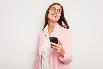 Business caucasian woman holding a mobile phone isolated on white background looks aside smiling, cheerful and pleasant.