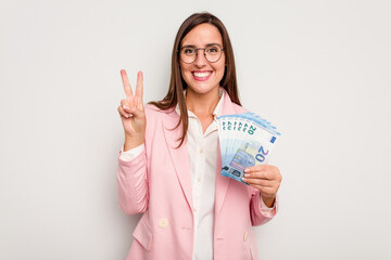 Business caucasian woman holding banknotes isolated on white background showing number two with fingers.