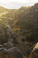 adventurous man walks on a long path between mountains in iceland