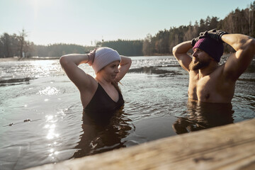 Caucasian couple swimming in frozen lake