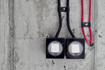 Close up concrete wall, old black and white light switch, black red cable on the wall, industrial interior design, copy space, black and red cable on top