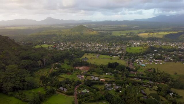 Aerial mountain sunrise footage. Epic cinematic nature aerial view of houses of Kauai island with green parakeets flying, Hawaii, USA. Kapaa town. 4k