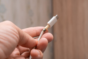 Close-up of the broken white Type-C charger cable to the phone. USB cable is damaged.