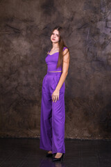 Portrait of a young beautiful brunette girl in purple pantsuit