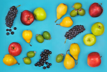  Set from  fresh ripe fruits apples, pears, fejhoa, black grapes on bright blue background. Top view, flat lay