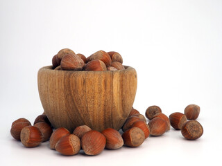 Hazelnuts in a wooden bowl on white background