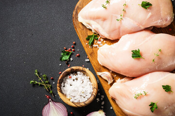 Chicken breast with spices at black background. Fresh raw meat. Top view with copy space.