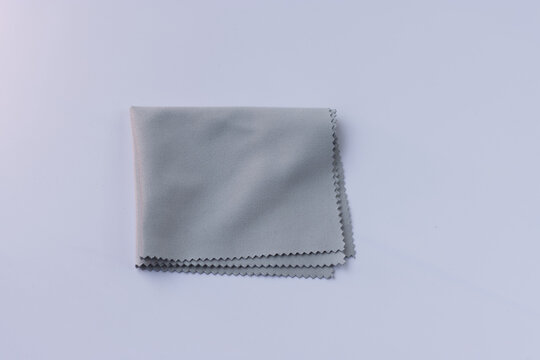 Microfiber cleaning cloth for glasses, eyeglass or camera lens isolated on white background. Grey micro fibre cloth.
