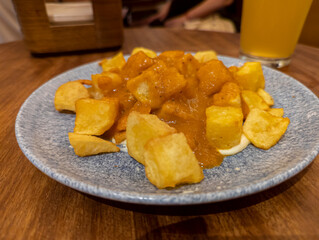 Typical Spanish dish called patatas bravas, fried tubers with red spicy sauce containing onion, paprika, oregano, chilli