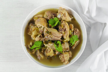 Homemade chicken soup with galangal,  lemon grass in white bowl.