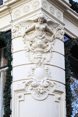 Fototapeta na wymiar Amsterdam Spui Square White Sculpted Decoration on a Building Depicting a Winged Woman with Bare Breasts, Netherlands