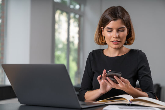 Inspired attractive businesswoman typing on smartphone at office workplace