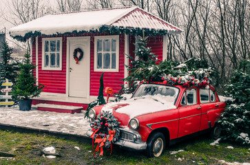 Decorated Santa's house with a red vintage car in the yard.