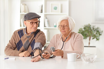 Elderly woman checking blood pressure to an elderly man