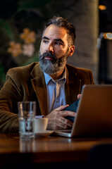 Portrait of businessman working in cafe using laptop.