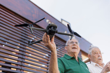 drone in primo piano e sullo sfonsdo due anziani signori che lo maneggiano