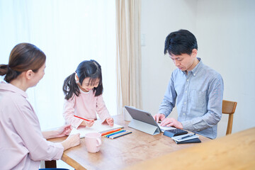 Fototapeta premium 部屋でお絵描きをして遊ぶ母娘と仕事をする父親