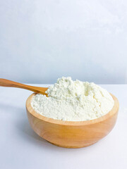 A wooden bowl of flour and flour spoon.