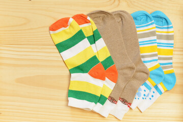 Different colors of children's socks on a plank surface