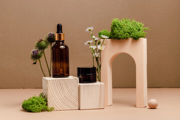 Cosmetic oil with face cream in dark amber bottles on wooden podium with plants and moss. Natural organic beauty products, beige wall background