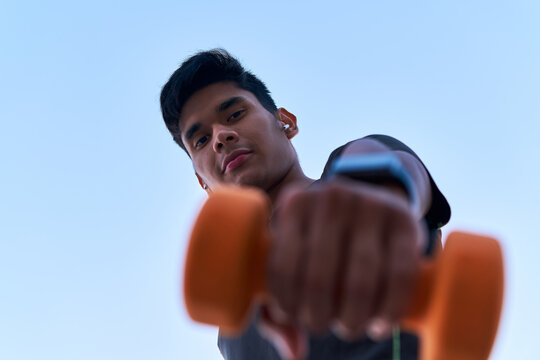 Low view of a young man holding a dumbbell