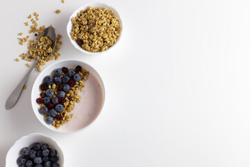 There is yogurt on the table in a plate. Sprinkled with blueberries and granola.