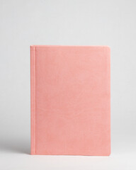 Pink diary standing on table on white background. Front side