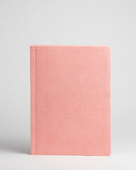 Pink diary standing on table on white background. Front side