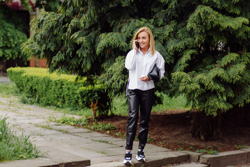 Happy young beautiful woman using her smart phone walking on the city street