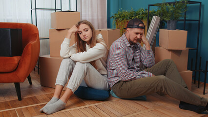 Sad tired married couple man woman leave house sit on floor near cardboard boxes with belongings stuff. Long relocation, bankruptcy, bank debt, eviction, division of property, divorce, hard moving day