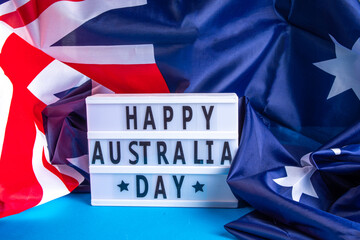 Fototapeta na wymiar Australia Day greeting card Background with australian flag, silver stars, lightbox with text Happy Australia day, paper red, blue, white decor, over blue background copy space
