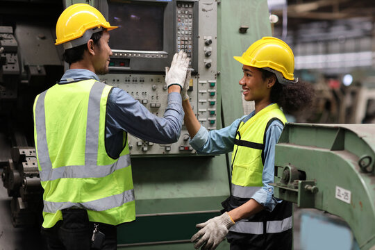 Happy smiling teamwork technician engineer or worker in protective uniform with hardhat give high five celebrate successful together completed deal commitment at heavy industry manufacturing factory